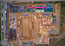 Aerial view of construction site with building materials stacked around two structures under construction