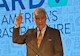 man in a suit points upward with his right hand