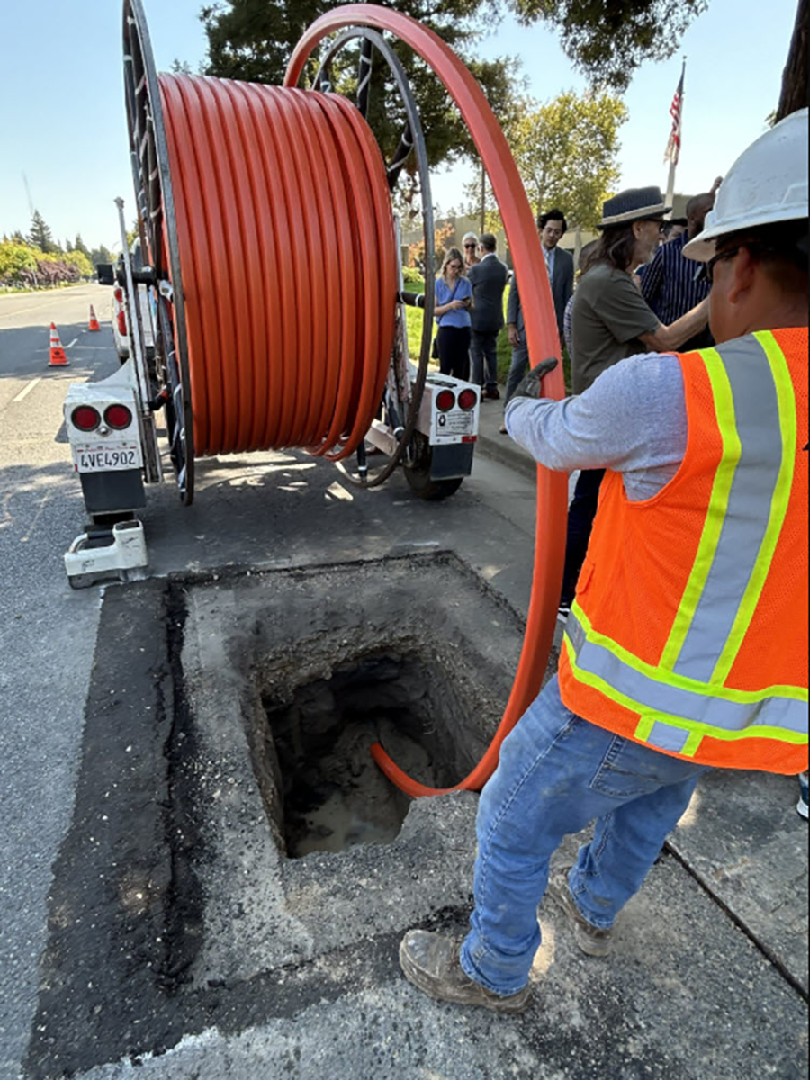 worker in orange vest and hardhat unspools tubing from a trailer worker in orange vest and hardhat unspools tubing from a trailer