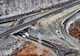aerial view of a highway project with work equipment and tree-lined areas