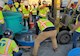 workers in hardhats and green work vests work with concrete